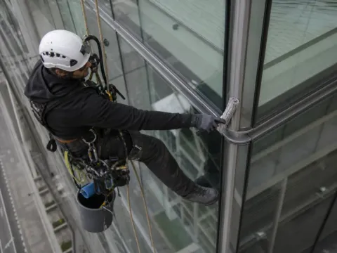 Spălare geamuri pe o fațadă curbă — alpinism utilitar